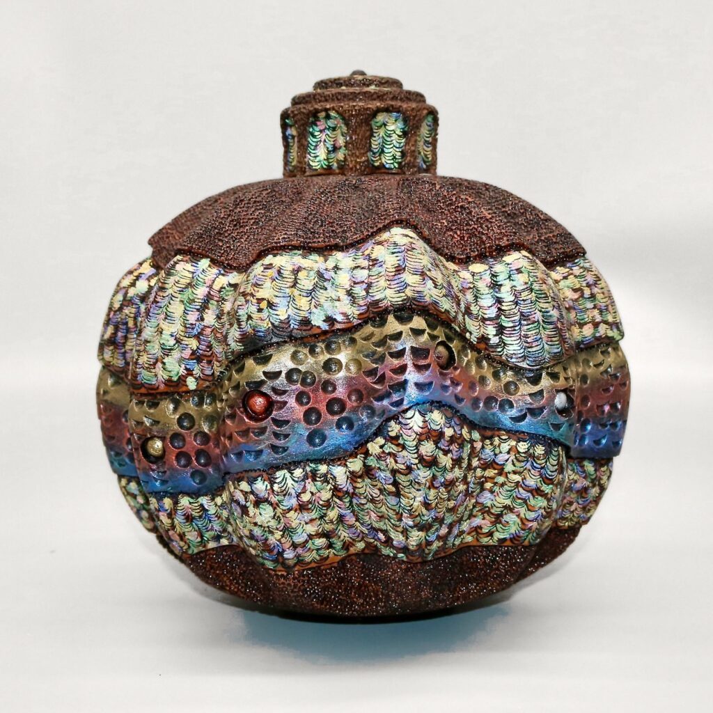 Another Angle, a round turned black walnut vessel with a small lidded top, wrapped in bands of iridescent painted texture